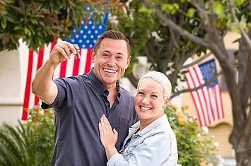 couple with keys to their new home and USA Flags in background